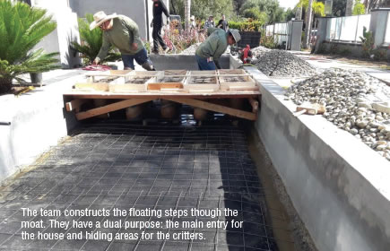 Floating steps being created across a moat from the house.